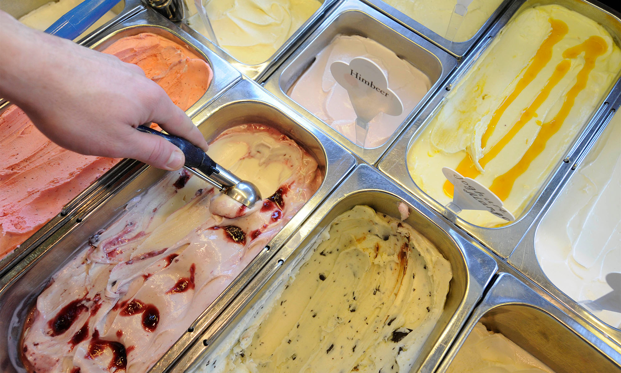 Mitarbeiter einer Eisdiele benutzt einen Eisportionierer.