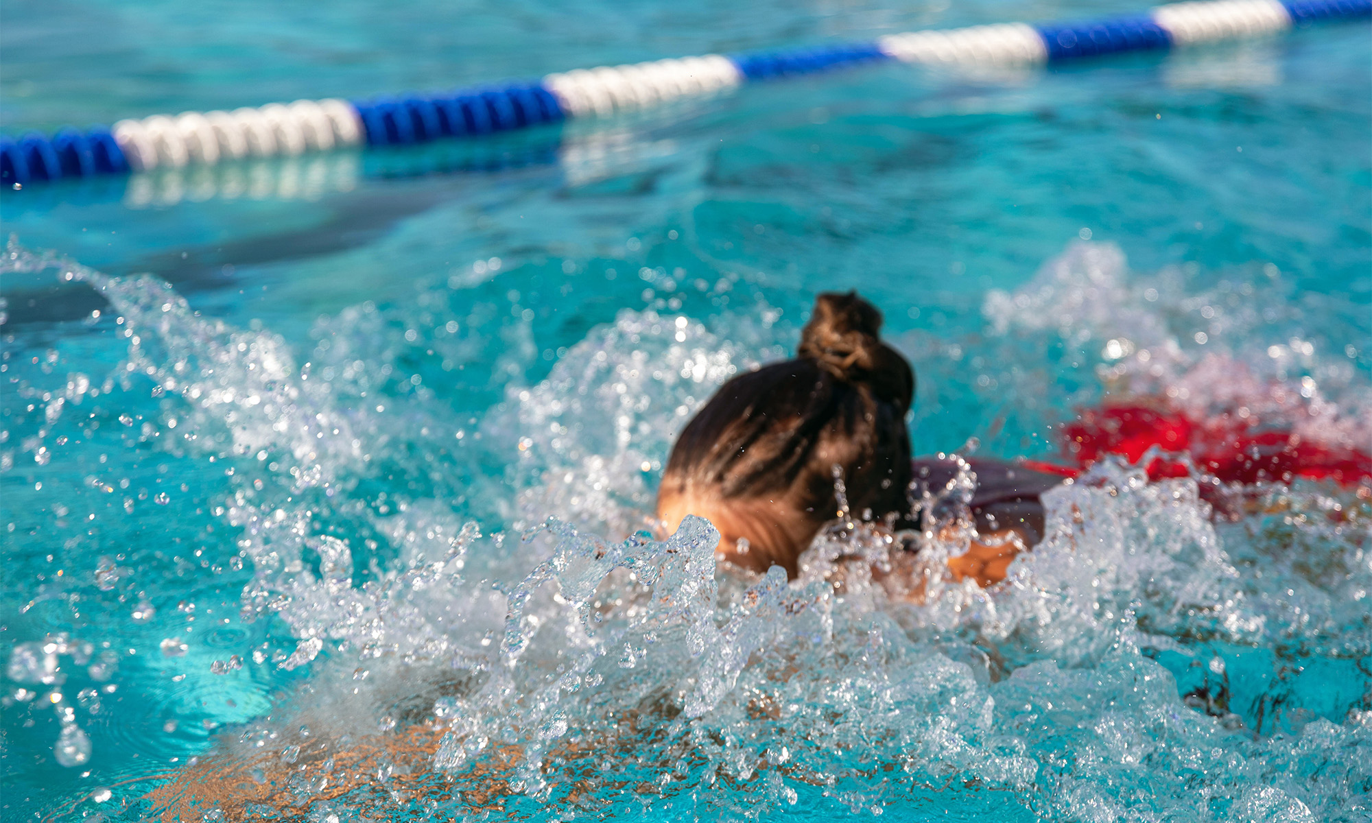 Eine junge Frau schwimmt auf einer Bahn in einem Freibad
