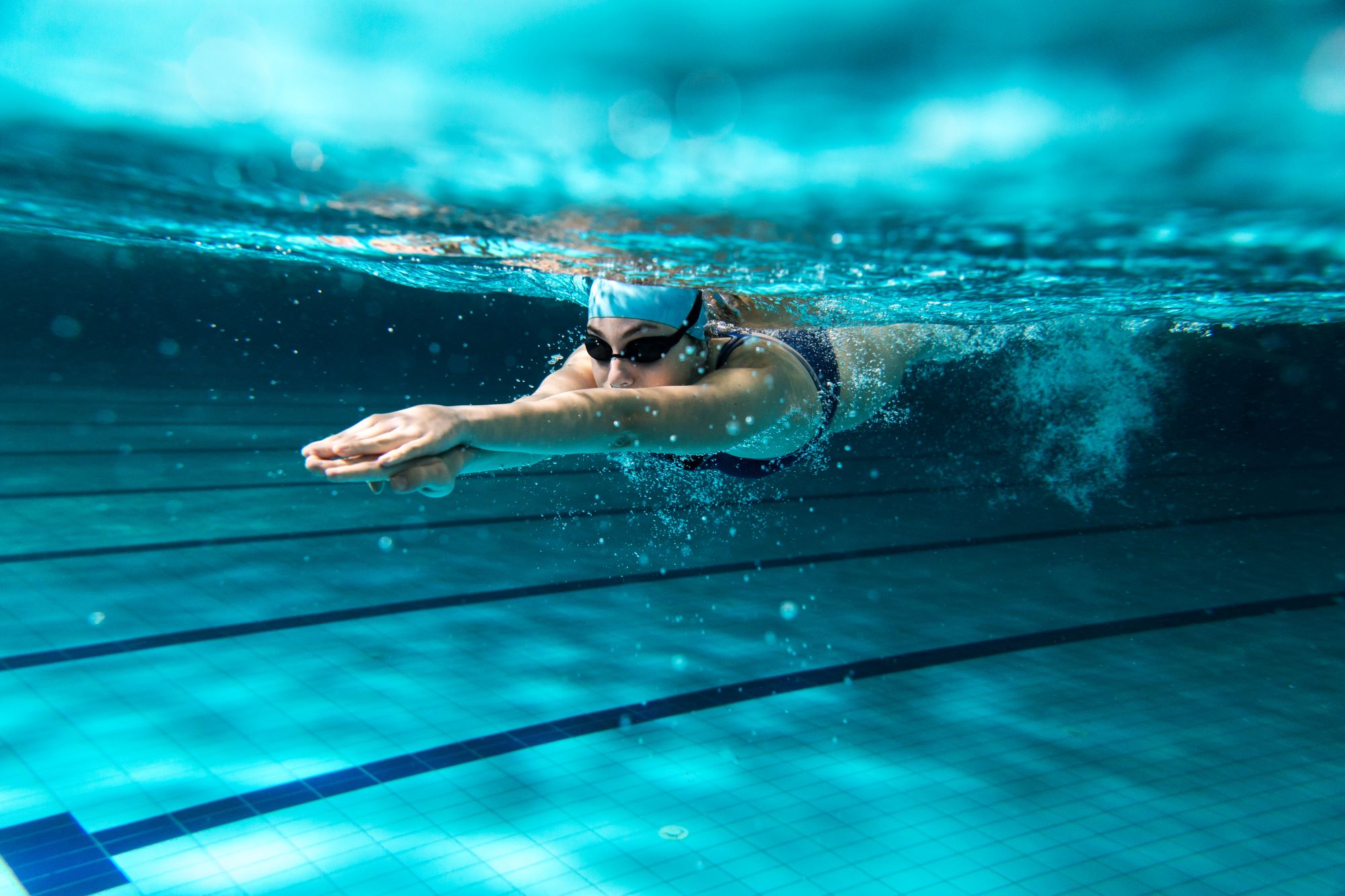 Mehrere Personen schwimmen auf einer Luftmatratze im Fühlinger see, im Hintergrund der Sandstrand