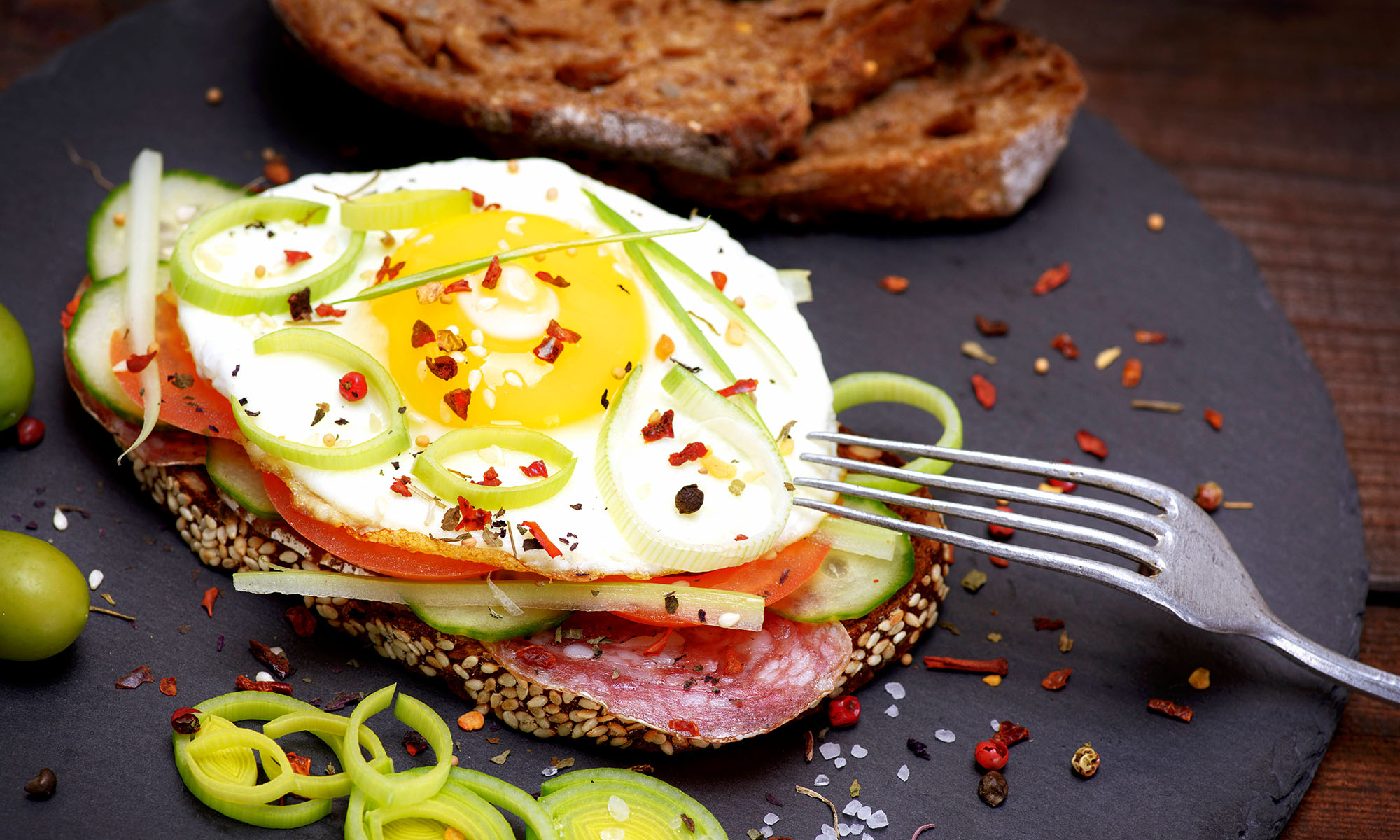 Ein Körnerbrot mit Belag und obendrauf einem Spiegelei.