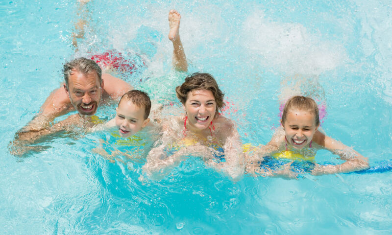 Eine Schwimmerin in gelbem Badeanzug zieht unter Wasser ihre Bahn.