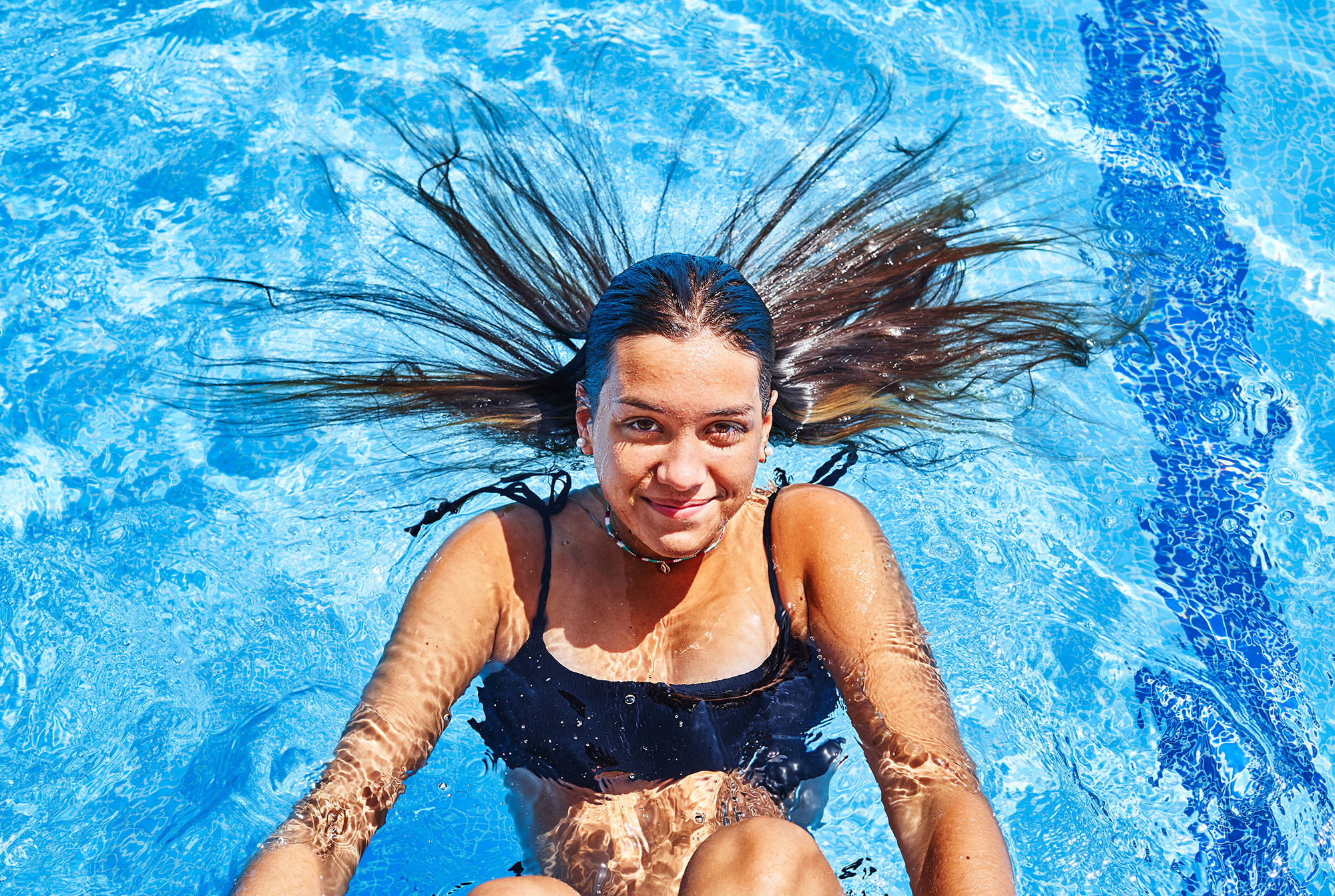 Das Bilder zeigt ein Mädchen, auf dem Rücken liegend, im Schwimmbecken.