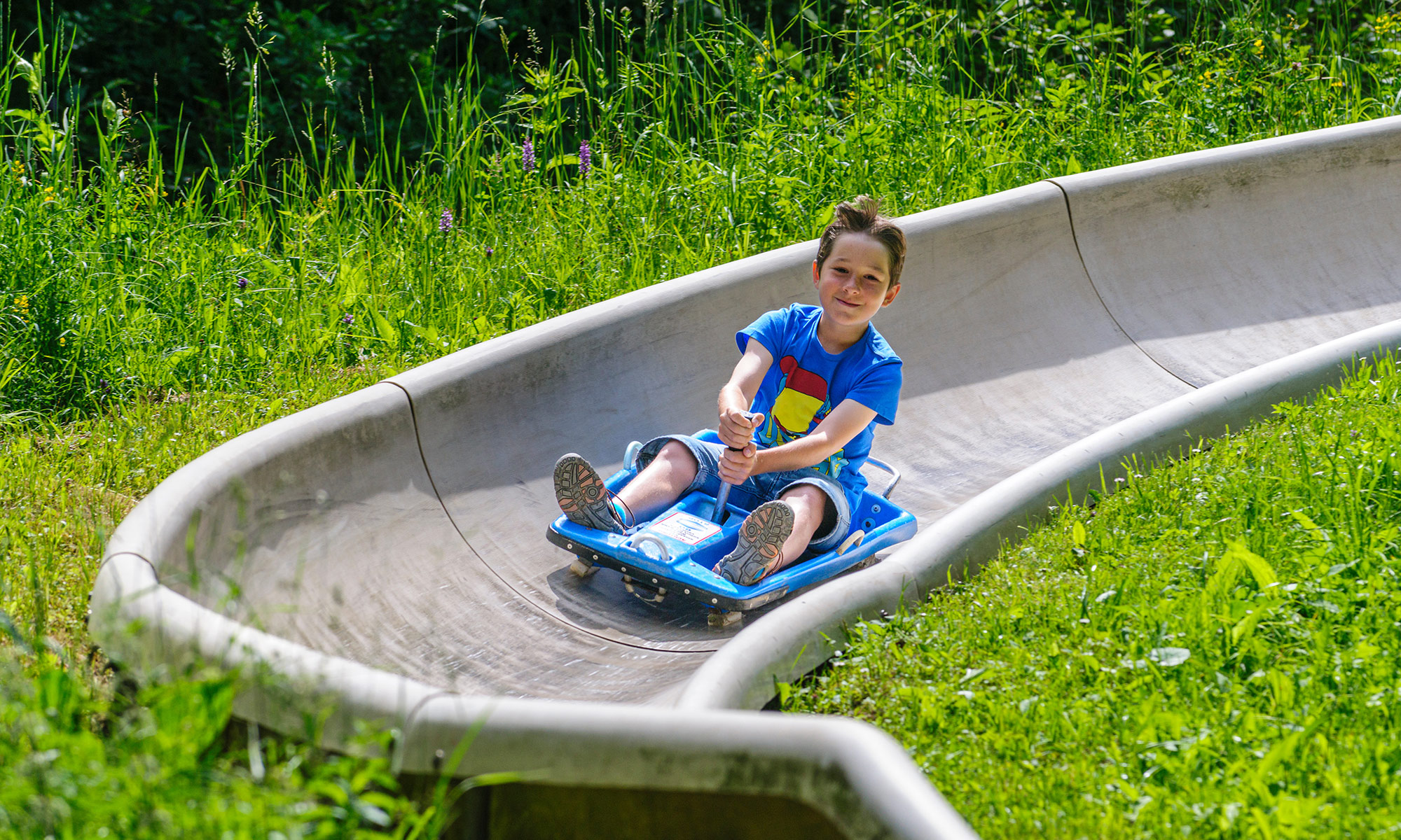 Ein Junge fährt eine Sommerrodelbahn hinab.