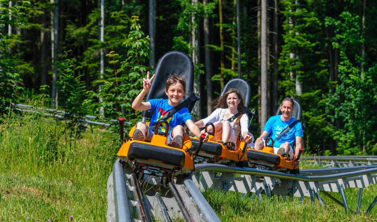 Eine Familie fährt eine Sommerrodelbahn hinab