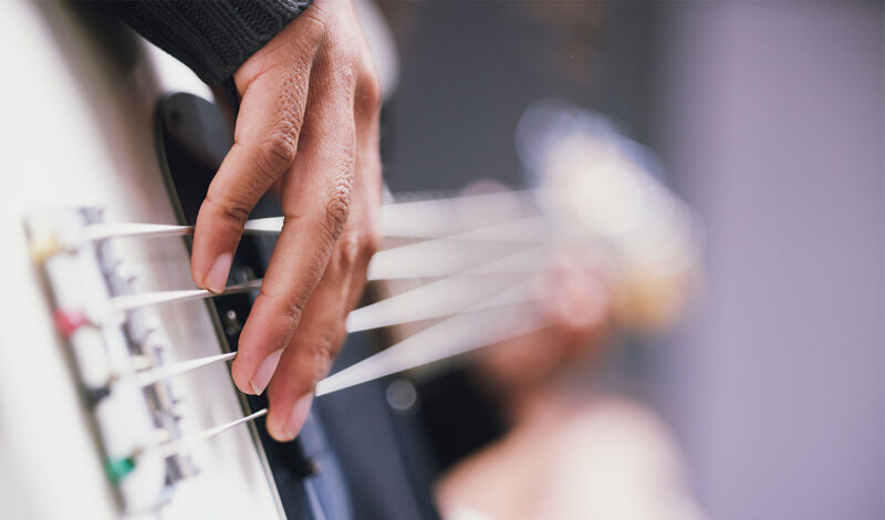 Das Bild zeigt eine Großaufnahme der Hand eines Mannes, welcher Bass spielt