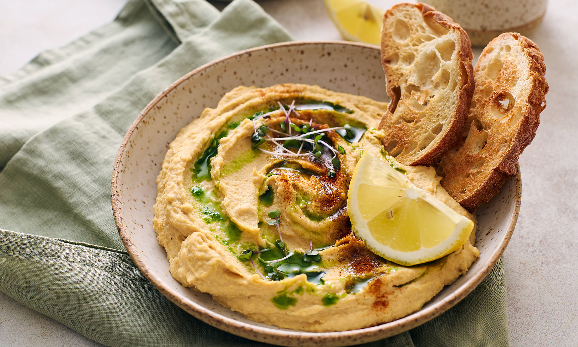 Hummus mit Öl, Zitrone und geröstetem Brot.