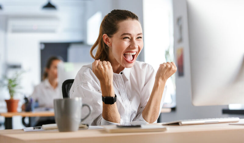 Das Bild zeigt eine Frau am Computer, die sich freut