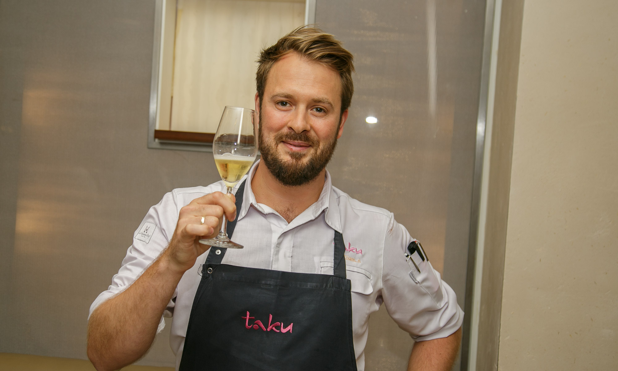 Der Sternekoch Mirko Gaul, Küchenchef des Restaurants Taku, hält ein Glas Champagner in der Hand.