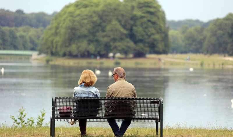 Eine Frau und ein Mannsitzen auf einer Parkbank und blicken auf den Decksteiner Weiher