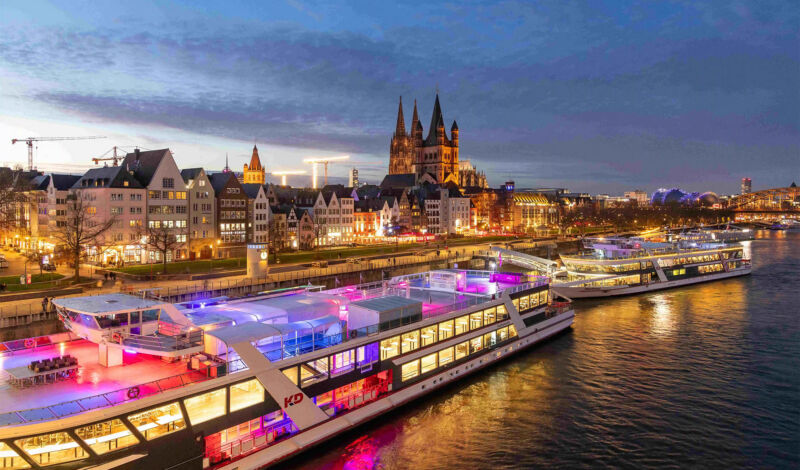 Beleuchtete Schiffe liegen am Kölner Altstadtufer vor Anker