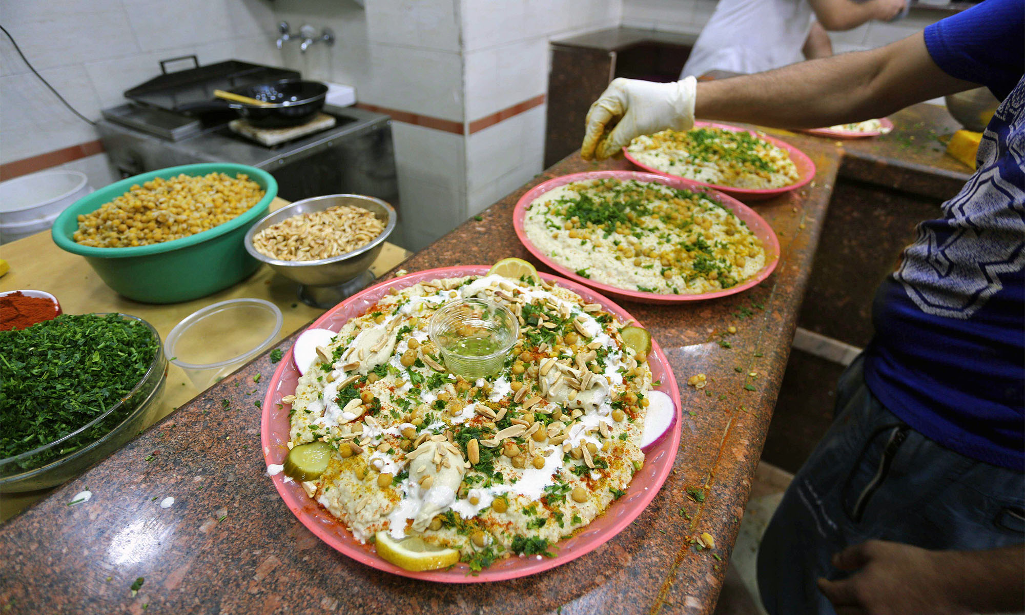 Mitarbeiter eines Imbisses bereiten Teller mit Hummus vor
