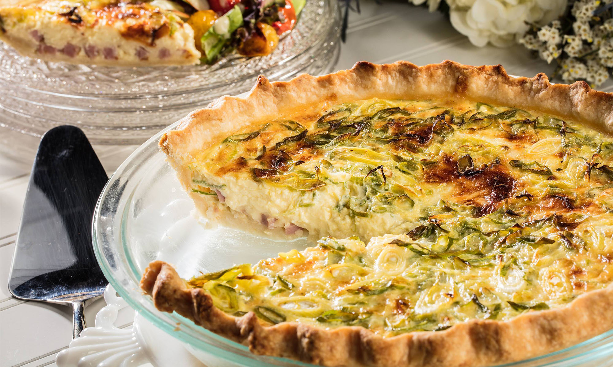 Eine klassische Quiche Lorraine, aus welcher ein Stück herausgeschnitten wurde