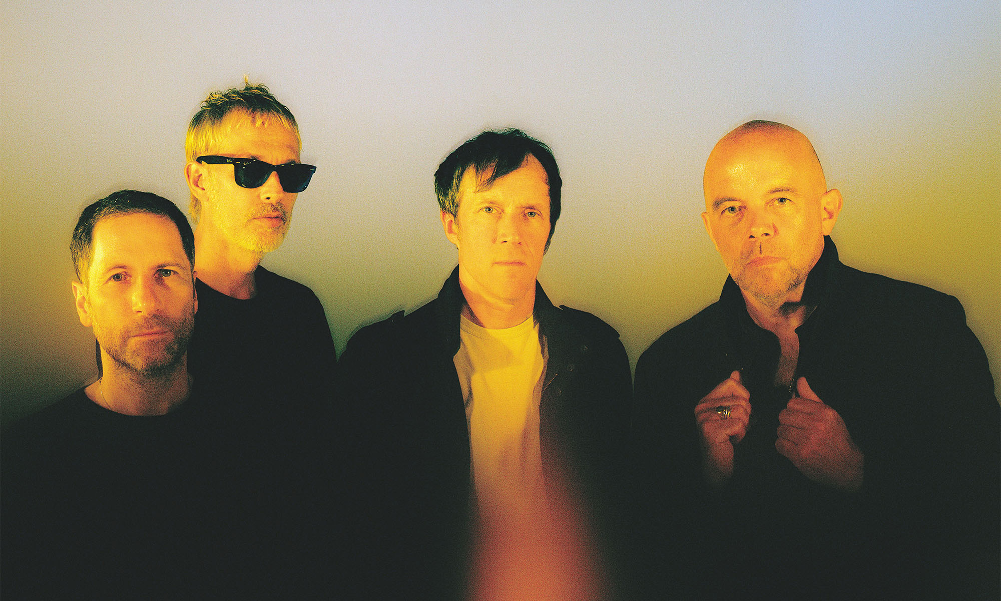 Die vier Musiker der britischen Band Ride in gelbes Licht getaucht.