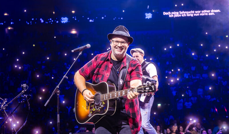 Björn Heuser mit Gitarre auf der Bühne.