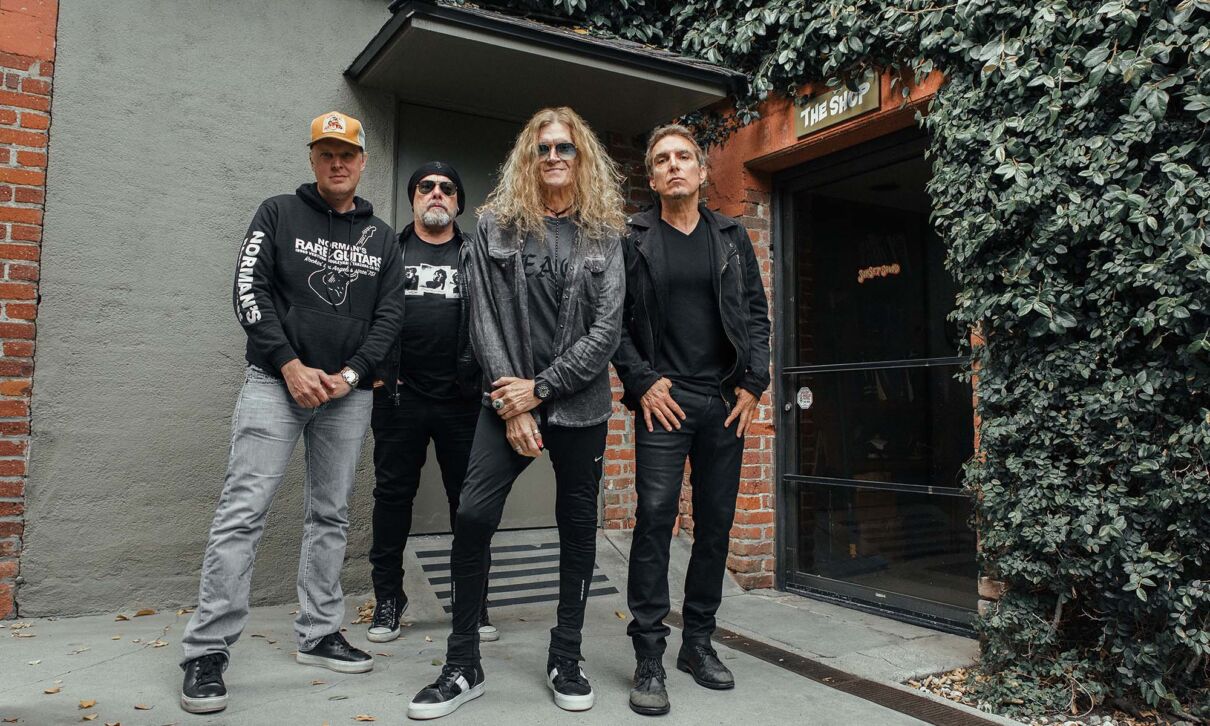 Die vier Musiker der Rock-Supergroup Black Country Communion stehen an einem Gebäudeeingang