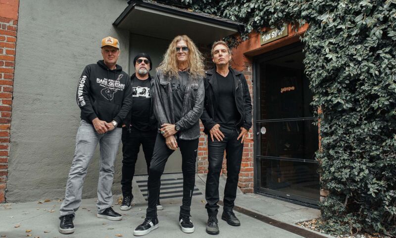 Die vier Musiker der Rock-Supergroup Black Country Communion stehen an einem Gebäudeeingang