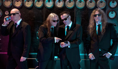 Die Musiker der deutschen Metalband Blind Guardian in schwarzen Anzügen.