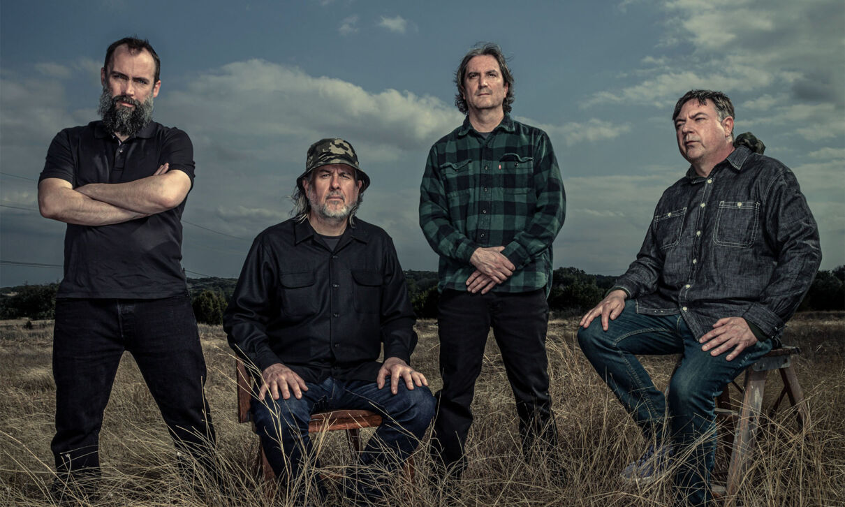 Die Msuiker der uS-Band Clutch auf einer Wiese in einer weiten LAndschaft.