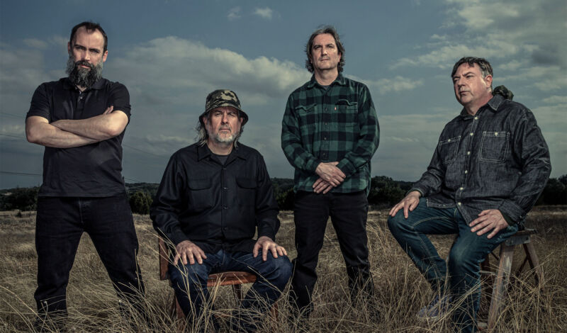 Die Msuiker der uS-Band Clutch auf einer Wiese in einer weiten LAndschaft.