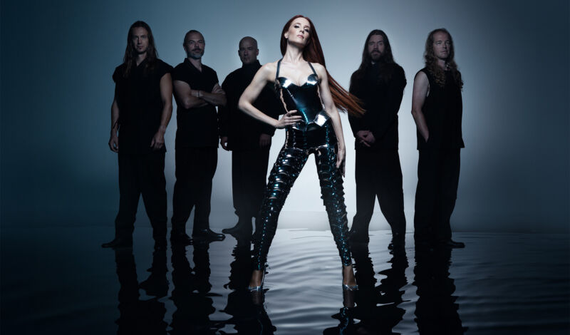 Die Mitglieder der Symphonic-Metal-Band Epica stehen vor einem dunklen, grauen Hintergrund.