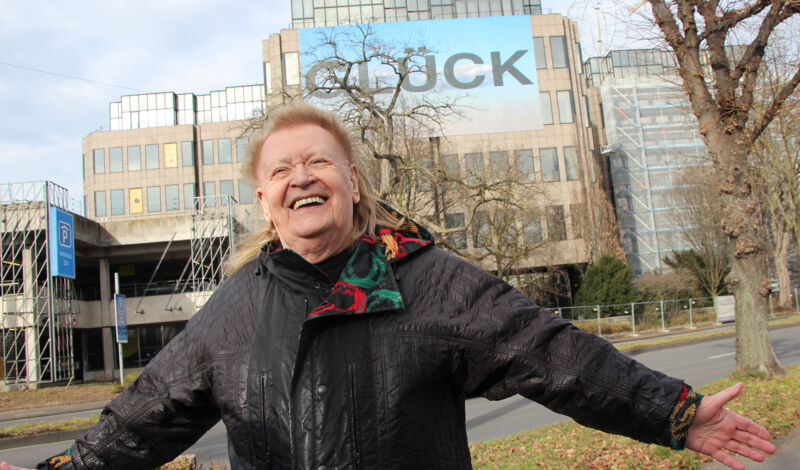 Künstler HA Schult vor seiner „mentalen Skulptur“ GLÜCK am DEVK-Versicherungsgebäude.