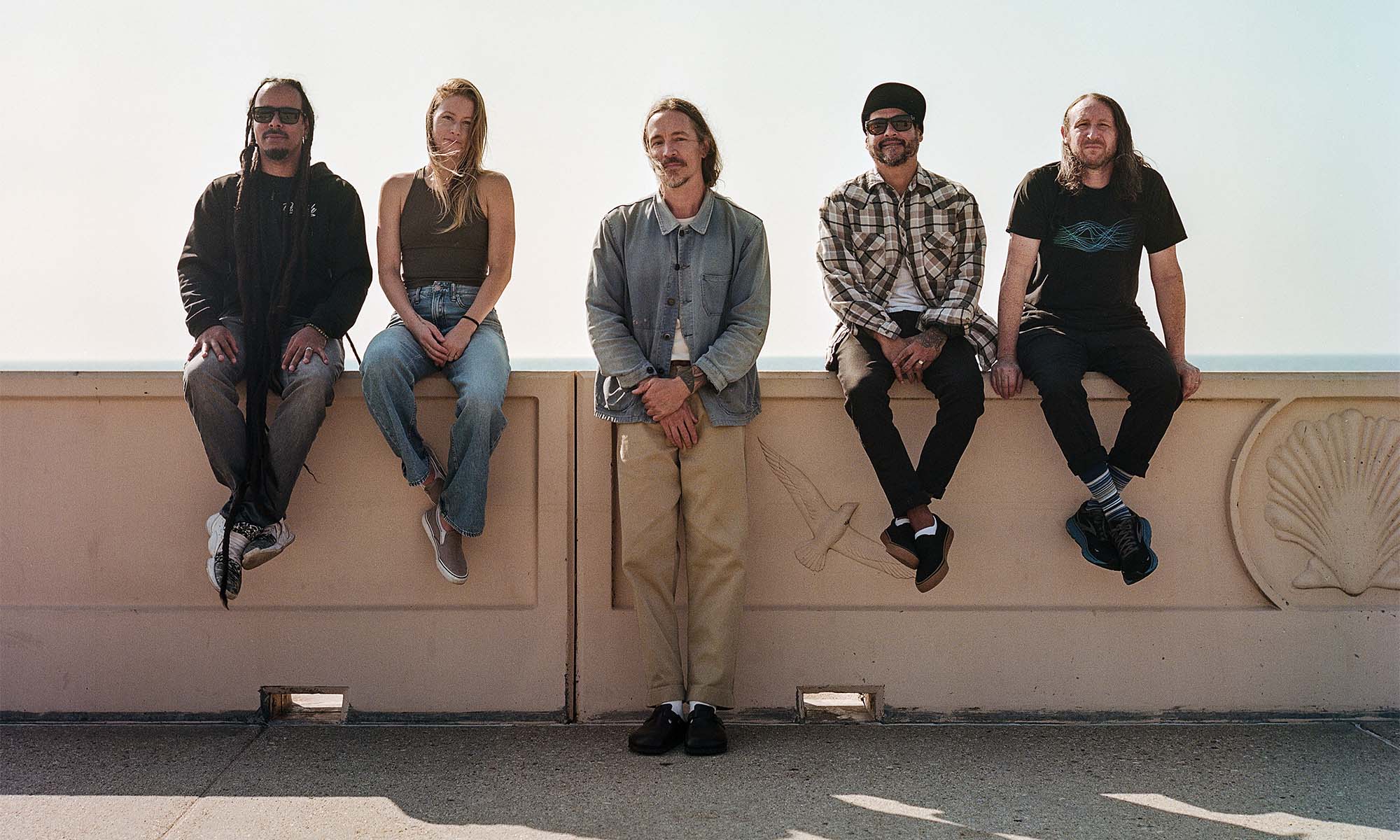 Die fünf Musiker der Band Incubus sitzen auf einer Mauer.