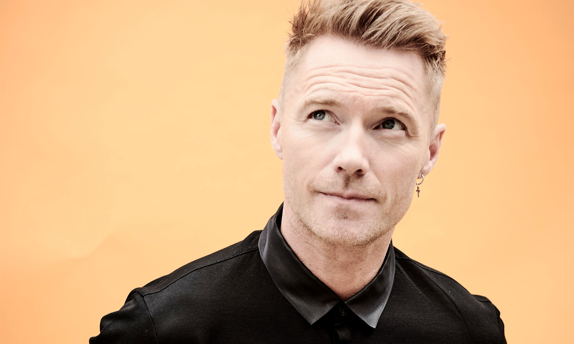 Der Sänger Ronan Keating in Großaufnahme vor einem beigen Hintergrund