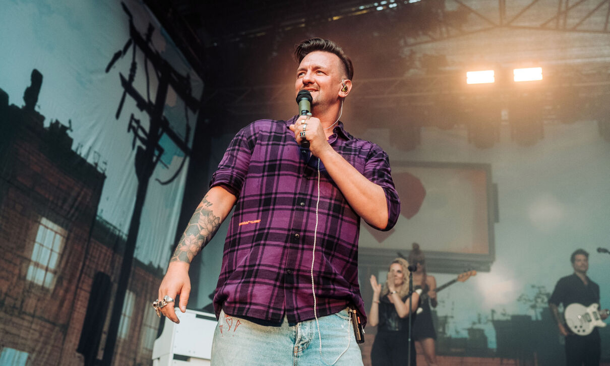 Schlagerpopsänger Ben Zucker in einem karierten Hemd auf der Bühne