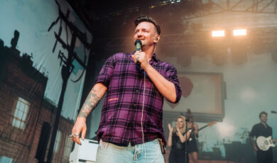 Schlagerpopsänger Ben Zucker in einem karierten Hemd auf der Bühne