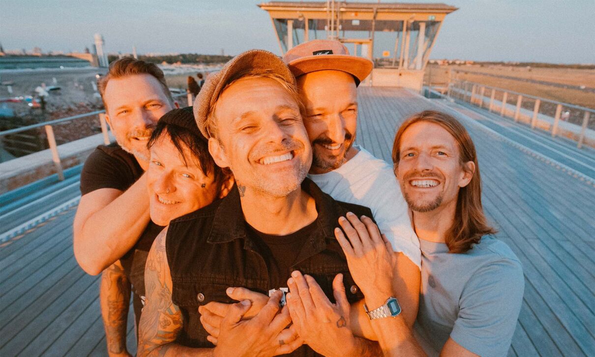 Die Musiker der Band Donots stehen lachend auf einem Schiffsdeck
