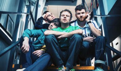 Die Musiker der Band Enter Shikari sitzen auf einer Treppe.