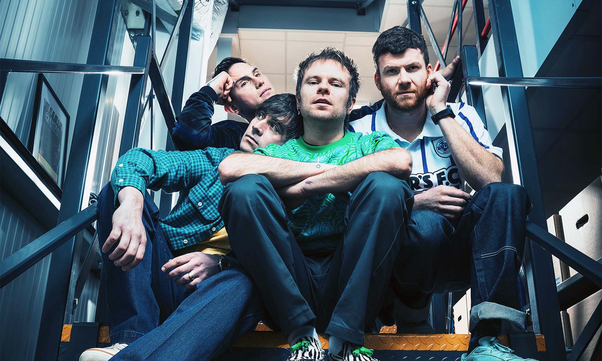 Die Musiker der Band Enter Shikari sitzen auf einer Treppe.