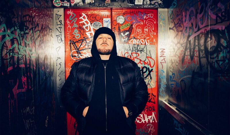 Der Rapper Kool Savas vor einer Türe in einem Underground-Club.