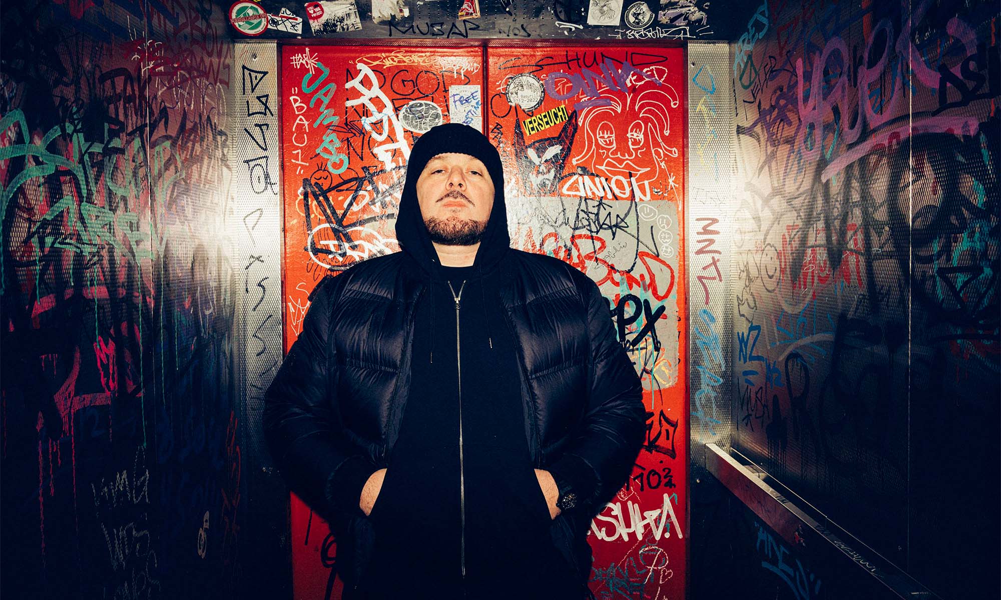 Der Rapper Kool Savas vor einer Türe in einem Underground-Club.