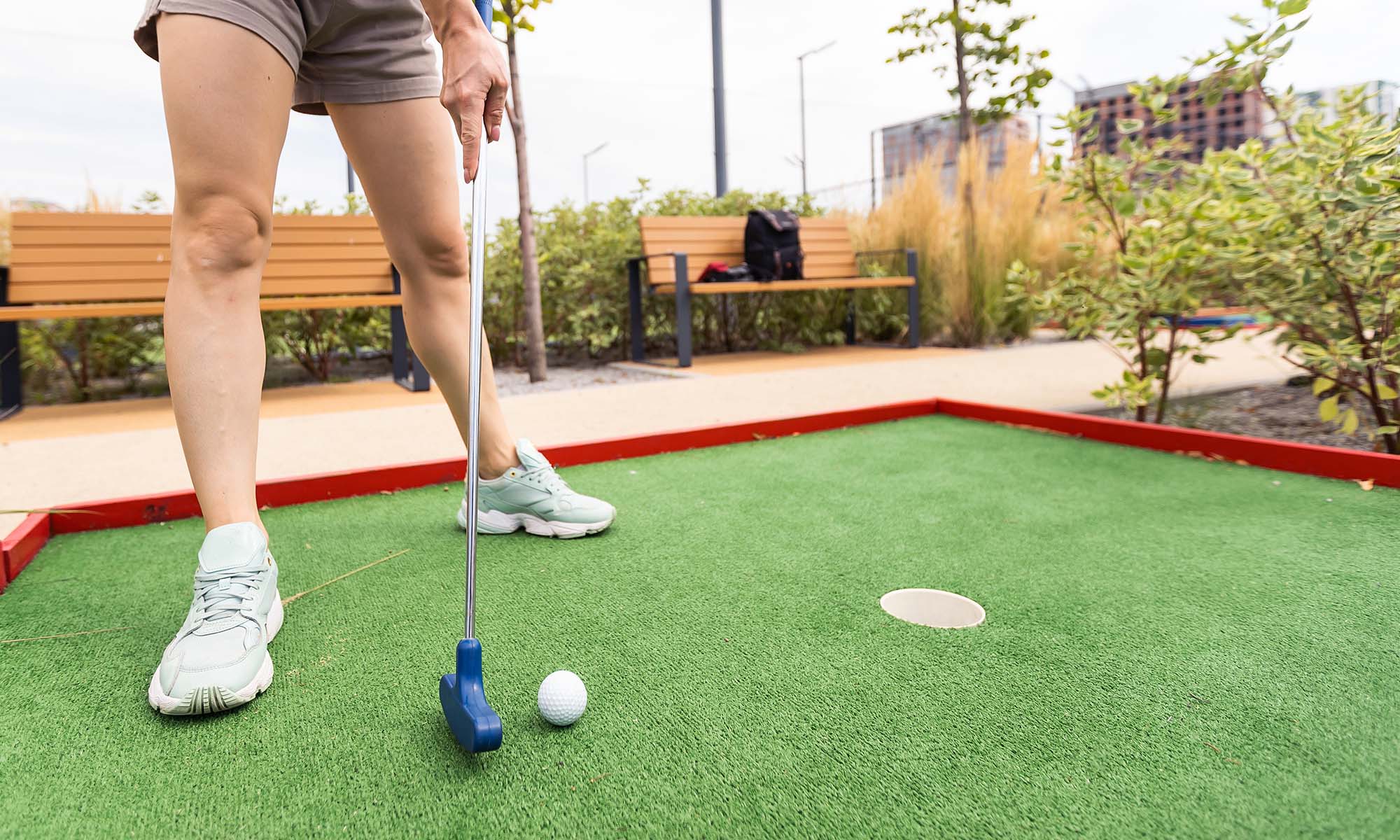 Ein Spieler versucht, den Ball auf einer Minigolfbahn mit dem Schläger ins Loch zu spielen