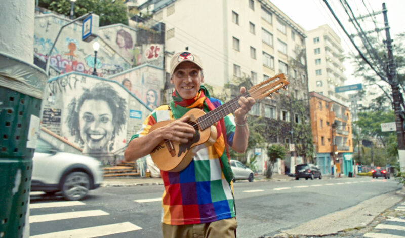 Der französisch-spanische Musiker Manu Chao steht mit einer Akustikgitarre auf einer Straße