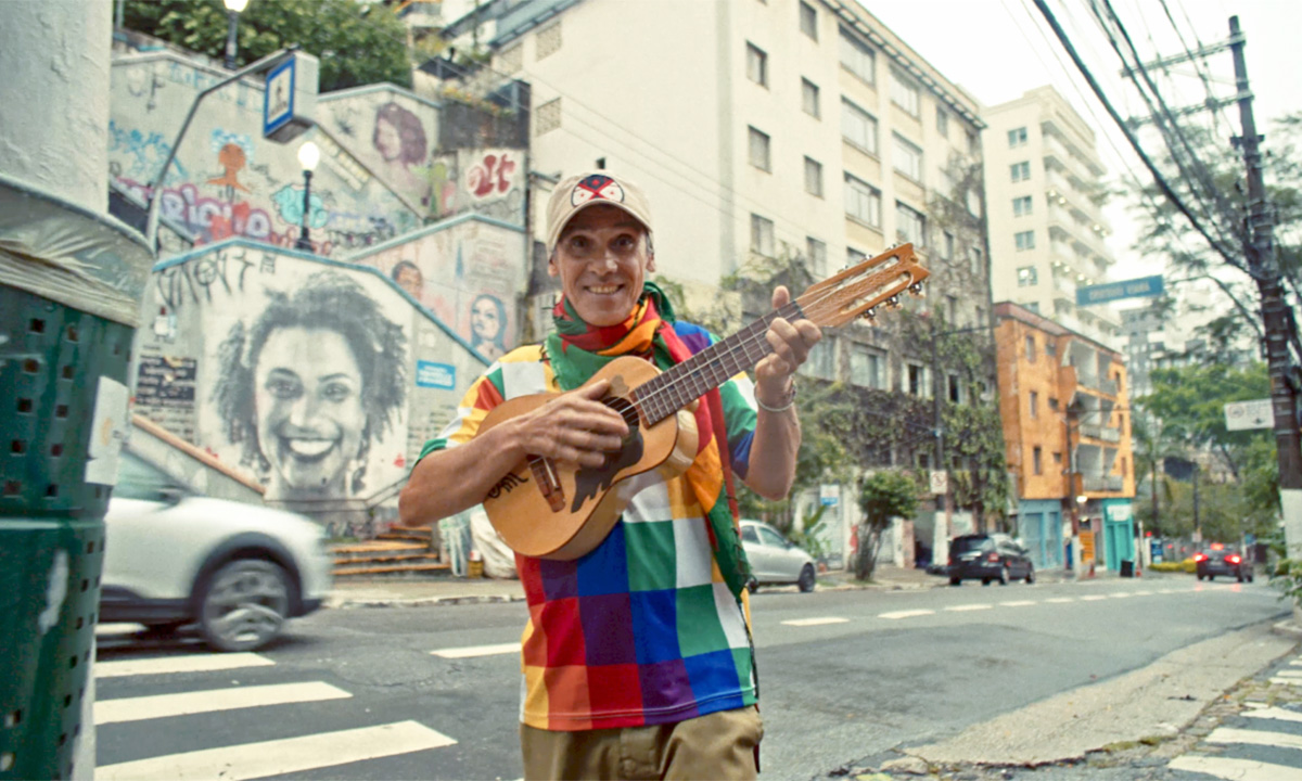 Der französisch-spanische Musiker Manu Chao steht mit einer Akustikgitarre auf einer Straße