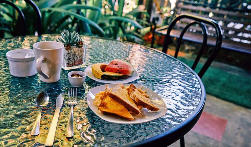 Toastbrot mit Rührei sowie Wassermelone auf einem Bistrotisch in einem Café