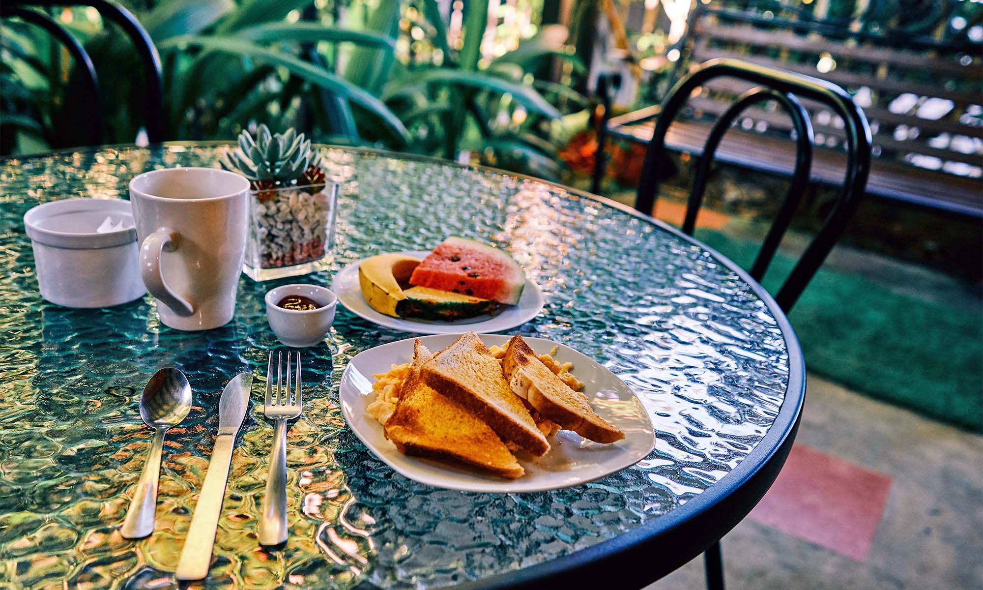 Toastbrot mit Rührei sowie Wassermelone auf einem Bistrotisch in einem Café