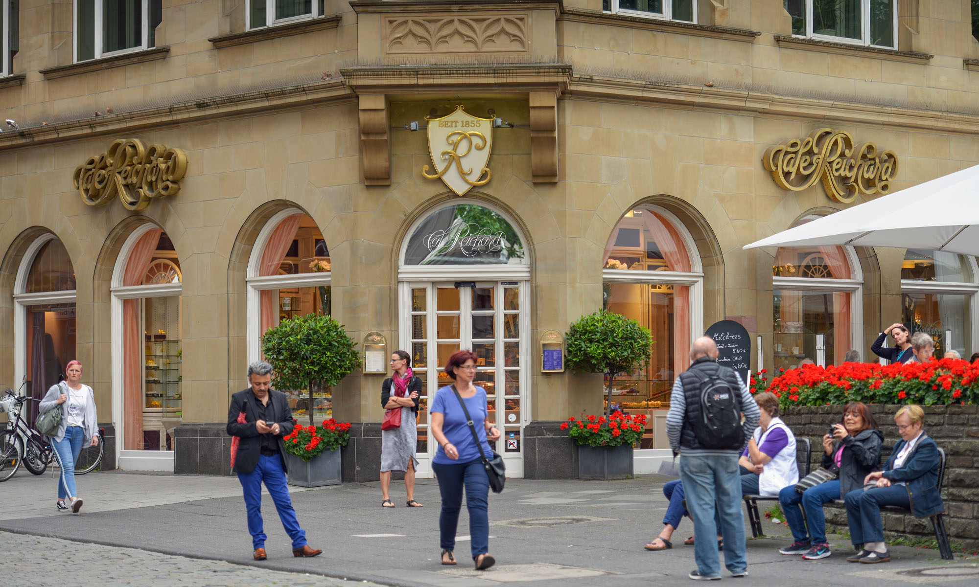 Passanten gehen vor dem Eingang des Cafés Reichard vorbei.