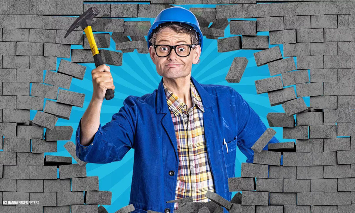 Eine Person mit einem Hammer blicht durch ein Loch im Mauerwerk