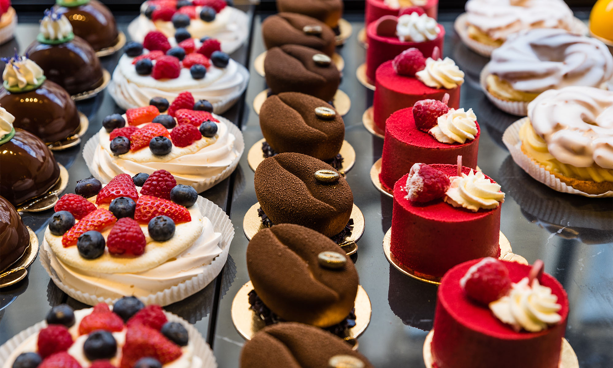 Feine Törtchen aus der Patisserie in der Theke einer Konditorei.