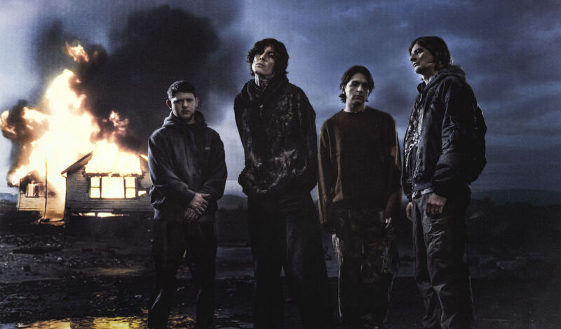 Musiker der britischen Metalband Bring me the Horizin stehen nachts vor einem brennenden Haus