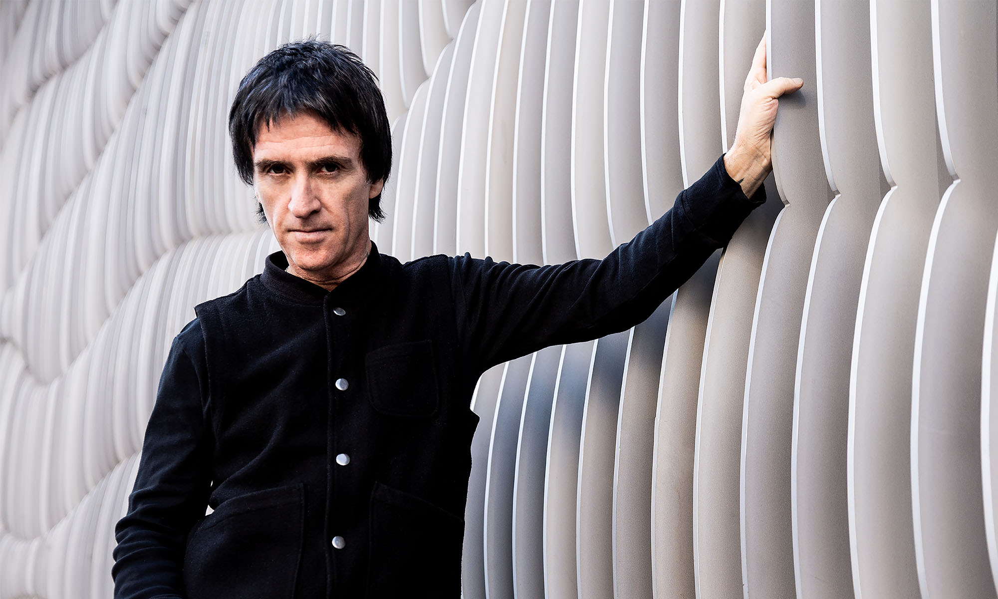 Der britische Songwriter und Gitarrist Johnny Marr lehnt an einer Wand.