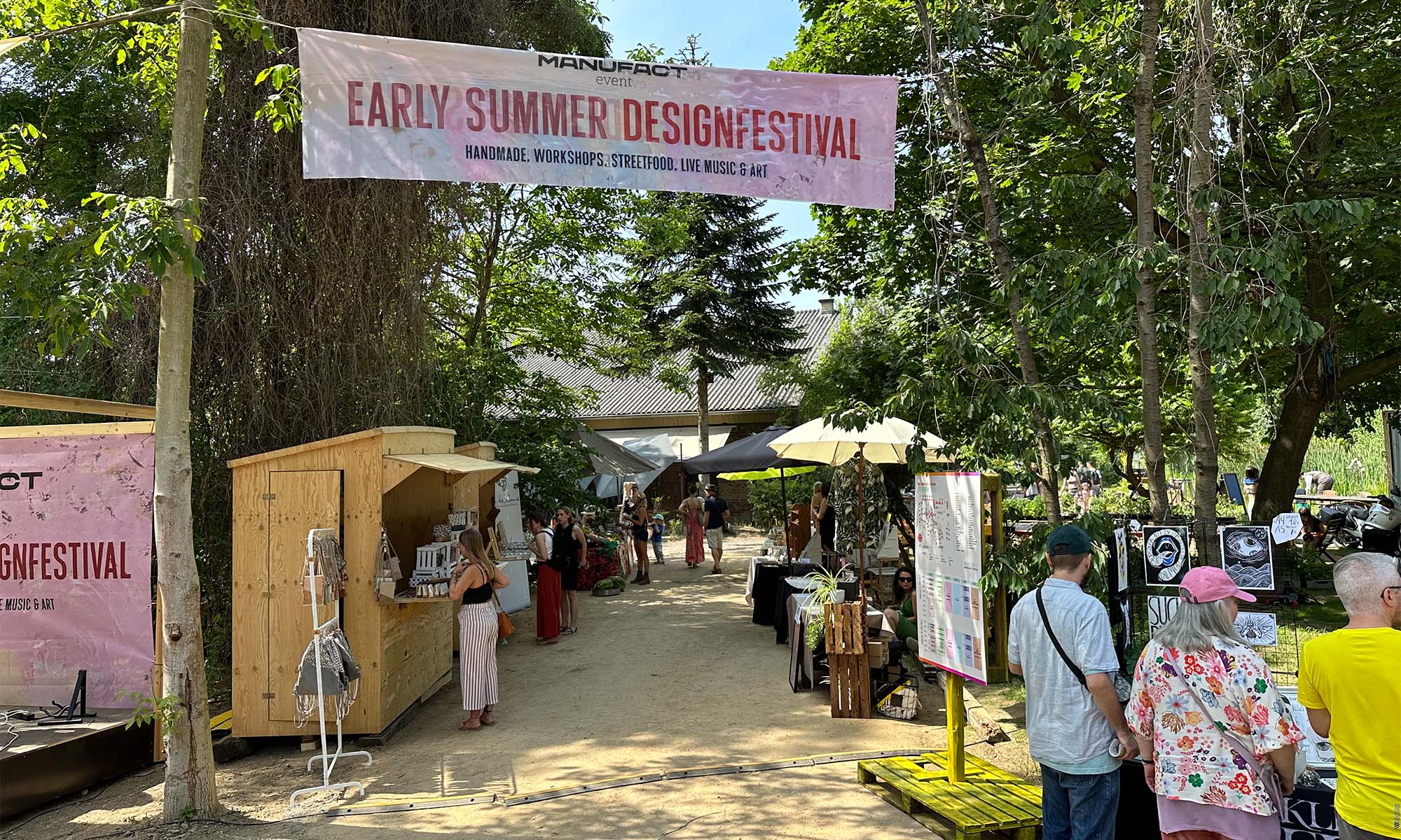 Besucher stöbern unter Bäumen an den Ständen des Early Summer Designfestivals