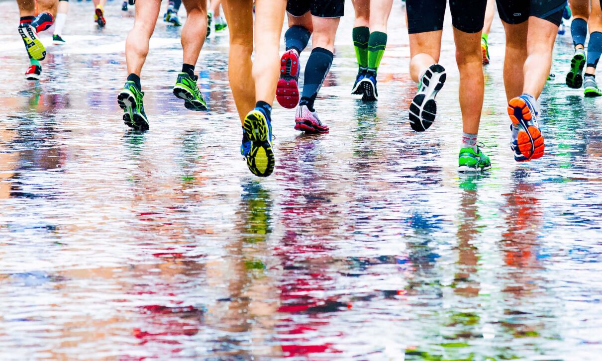 Läufer mit farbigen Schuhen joggen auf regennasser Straße