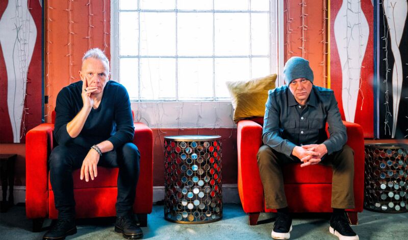 Die beiden Musiker von Mesh sitzen vr einem Fenster auf roten Sesseln.