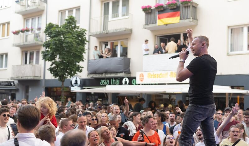 Beim Südstadtfest stehen Menschen vor einer Bühne, auf der ein Sänger steht
