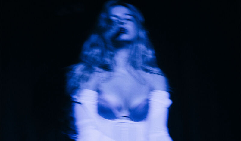 Ein sehr unscharfes Bild der Sängerin Addison Rae im blauen Scheinwerferlicht.
