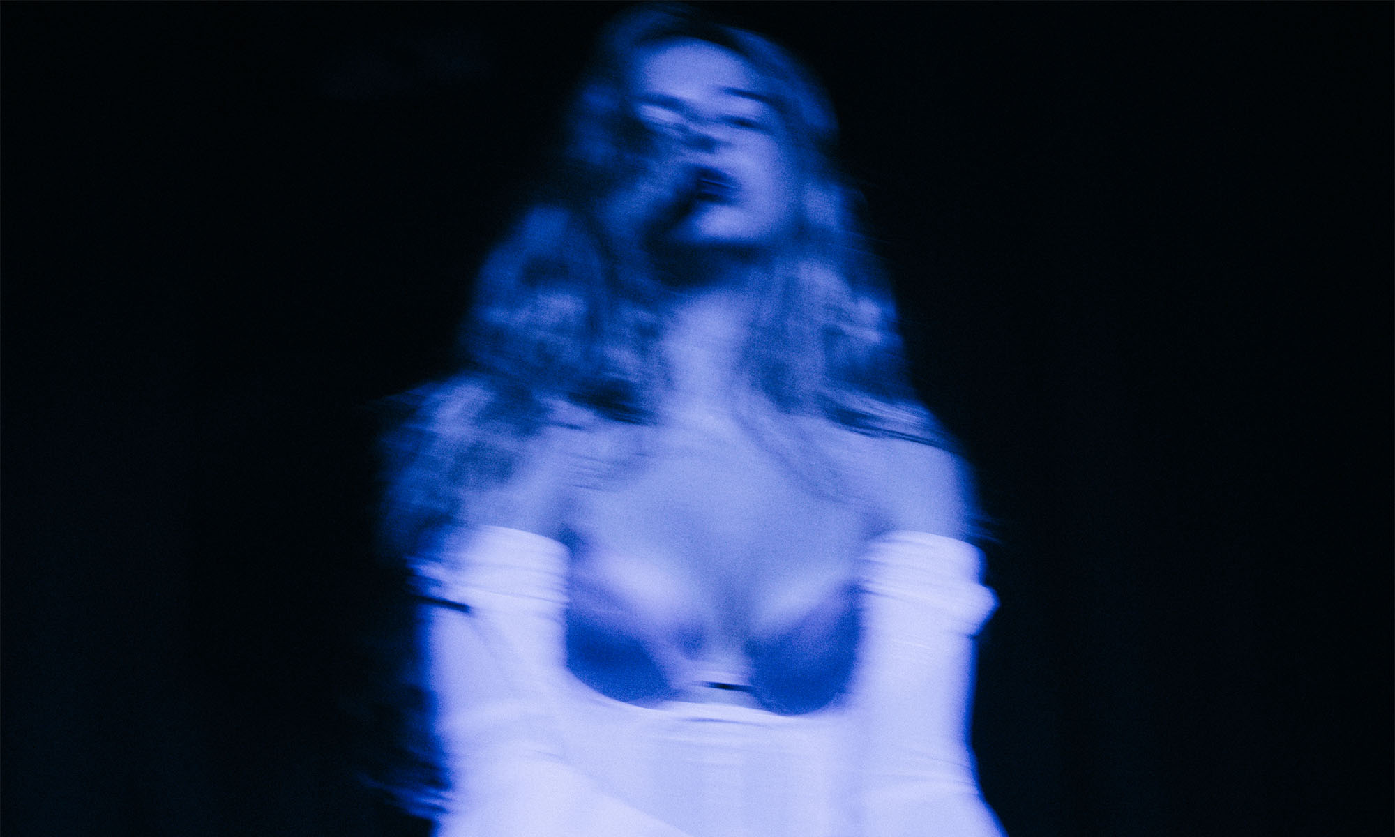 Ein sehr unscharfes Bild der Sängerin Addison Rae im blauen Scheinwerferlicht.
